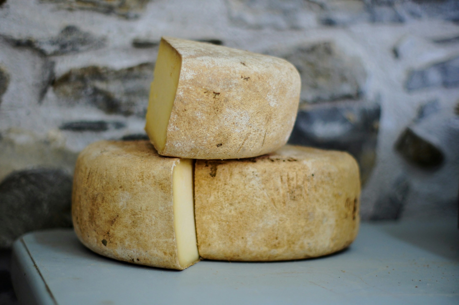 Stacked wheels of aged cheese against a stone cave wall
